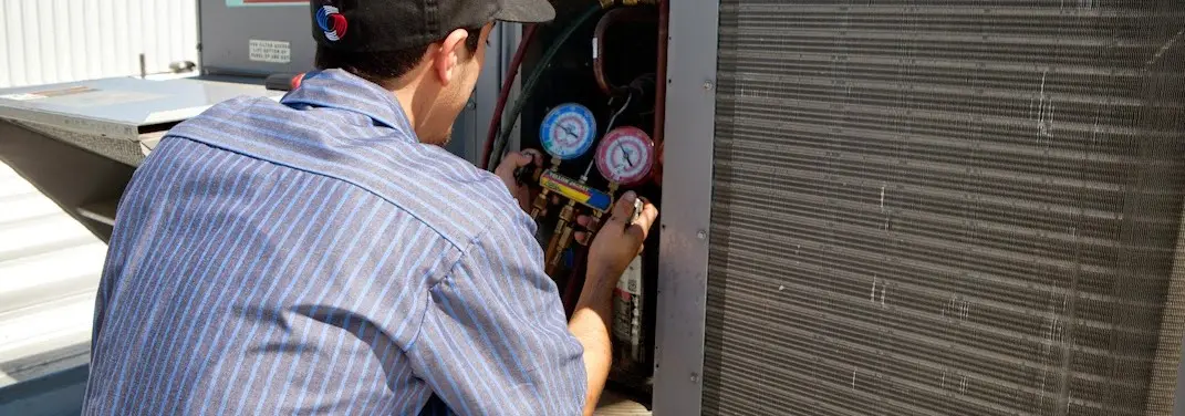 HVAC technician servicing a condenser unit in New River
