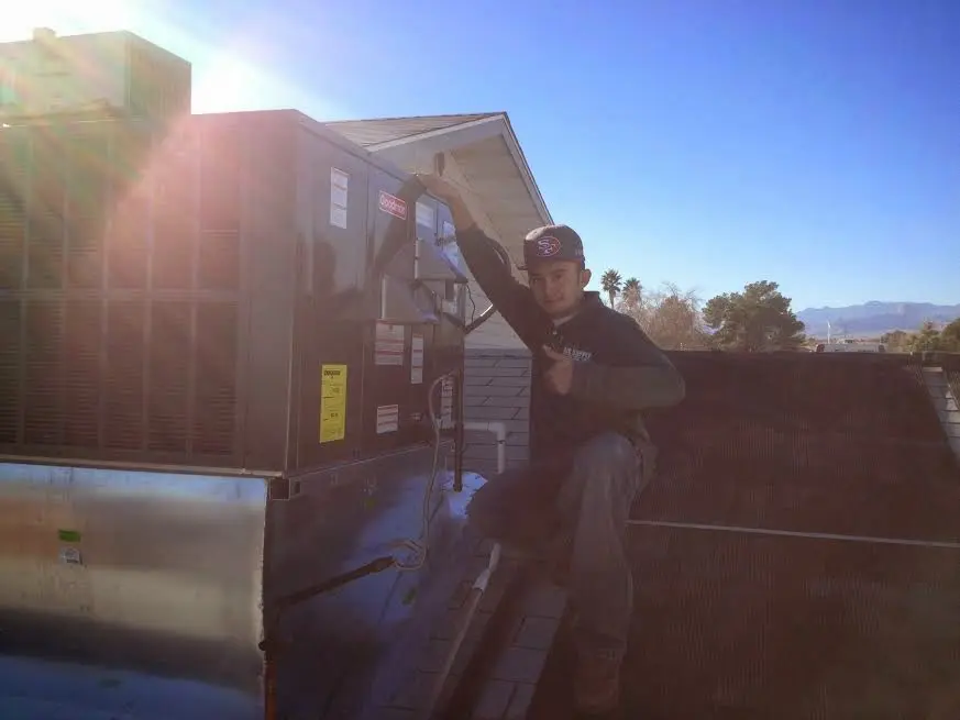 HVAC technician performing Air Duct Repair on a rooftop unit in New River